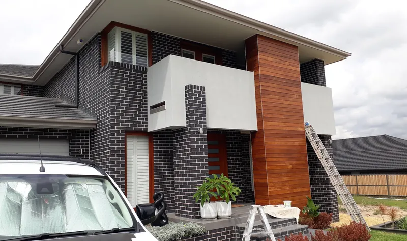 Exterior repaint in progress — ladders set up at a two-storey brick and timber-clad home — Westmead